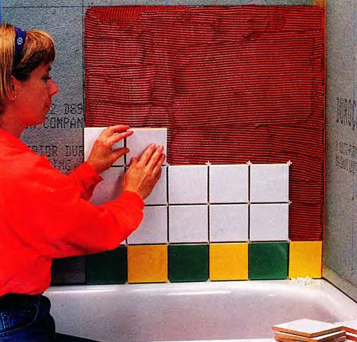 Woman setting ceramic tiles on bathroom walls